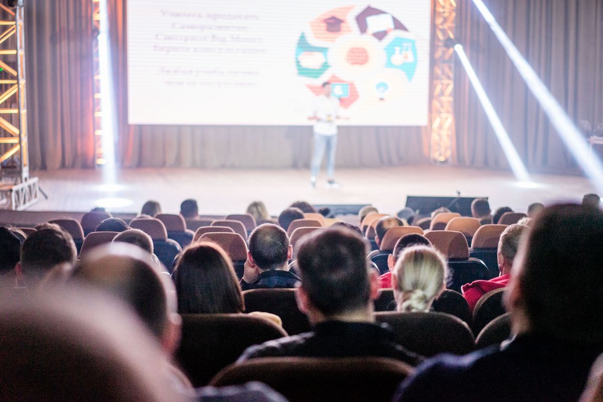 An audience watching a speaker at a conference